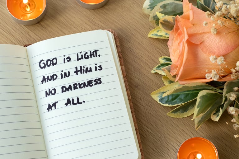 Cita cristiana 'Dios es luz' en cuaderno con flores y velas