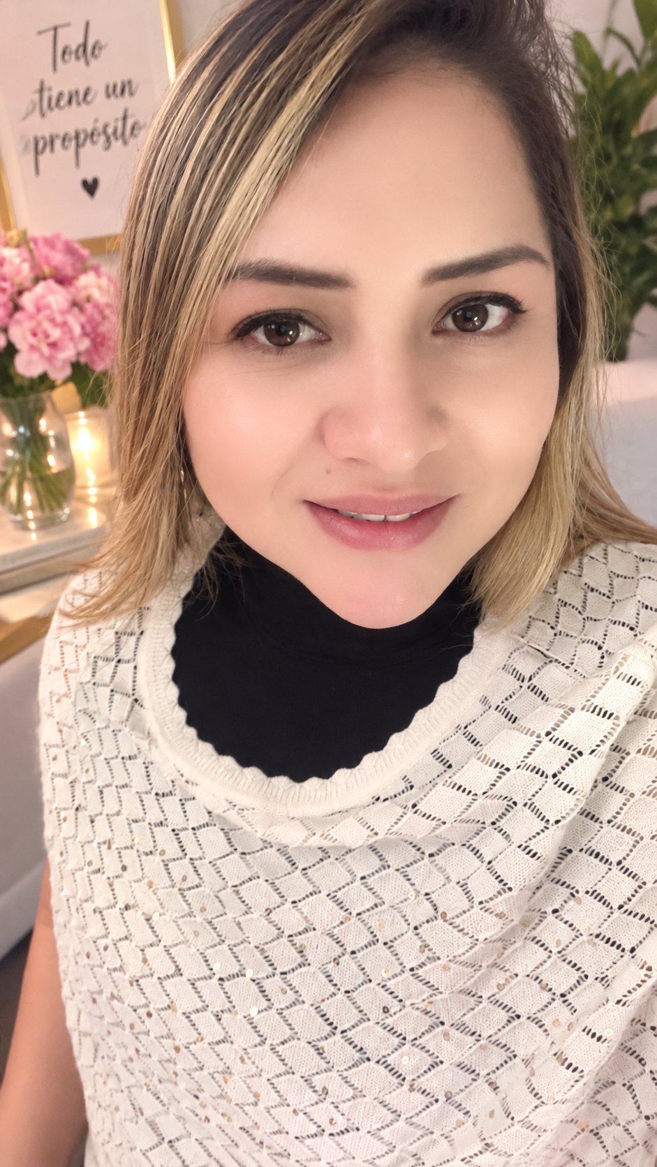 Retrato de una mujer sonriendo a la cámara con un suéter de textura crema